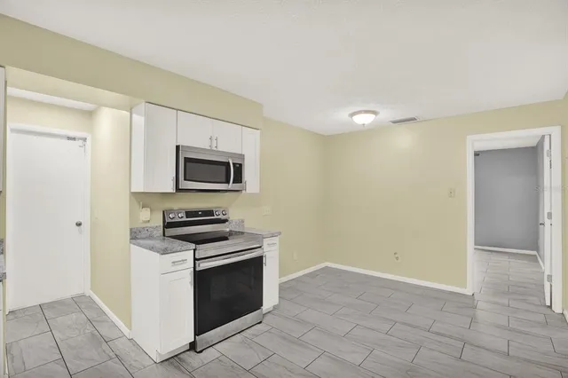 a kitchen with granite countertop white cabinets and stainless steel appliances
