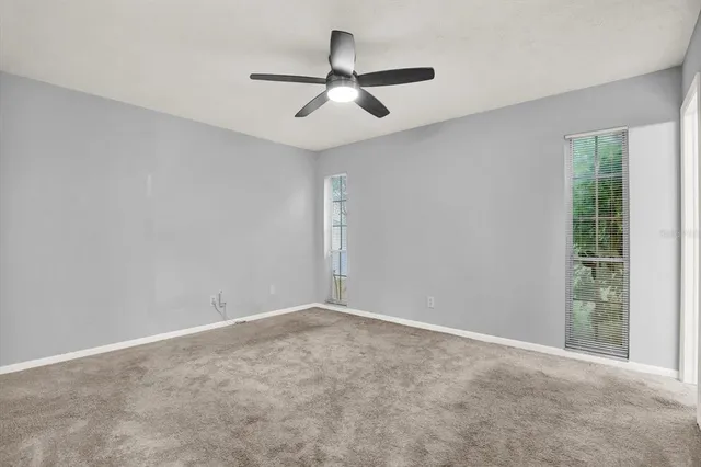 an empty room with a ceiling fan and window