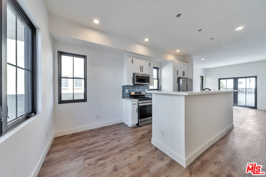 1022-1024 Masselin Avenue Los Angeles, CA 90036 - Photo 4 of 16 a kitchen with stainless steel appliances granite countertop a refrigerator a stove top oven a sink dishwasher and white cabinets with wooden floor
