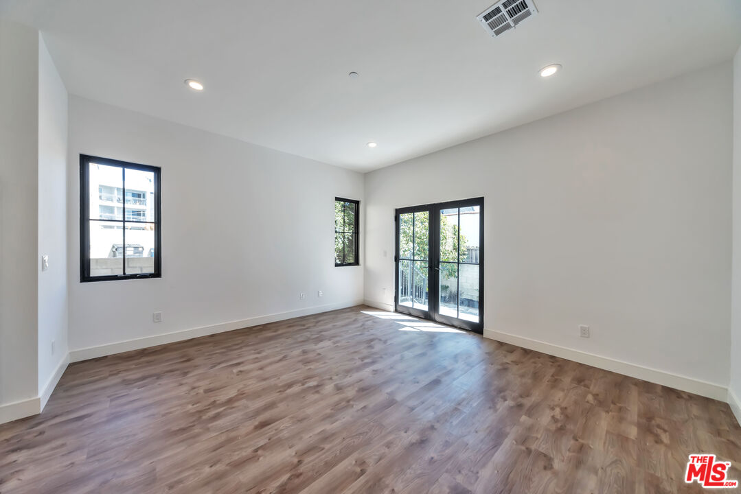 1022-1024 Masselin Avenue Los Angeles, CA 90036 - Photo 8 of 16 a view of an empty room with wooden floor and windows