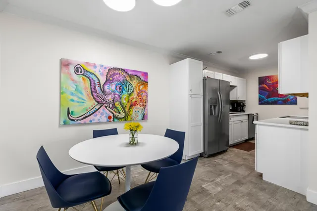 a kitchen with stainless steel appliances a refrigerator a sink a dining table and chairs