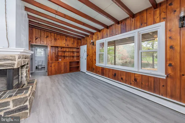 an empty room with wooden floor fireplace and windows