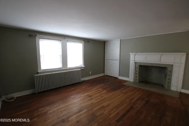 an empty room with wooden floor a fireplace and windows