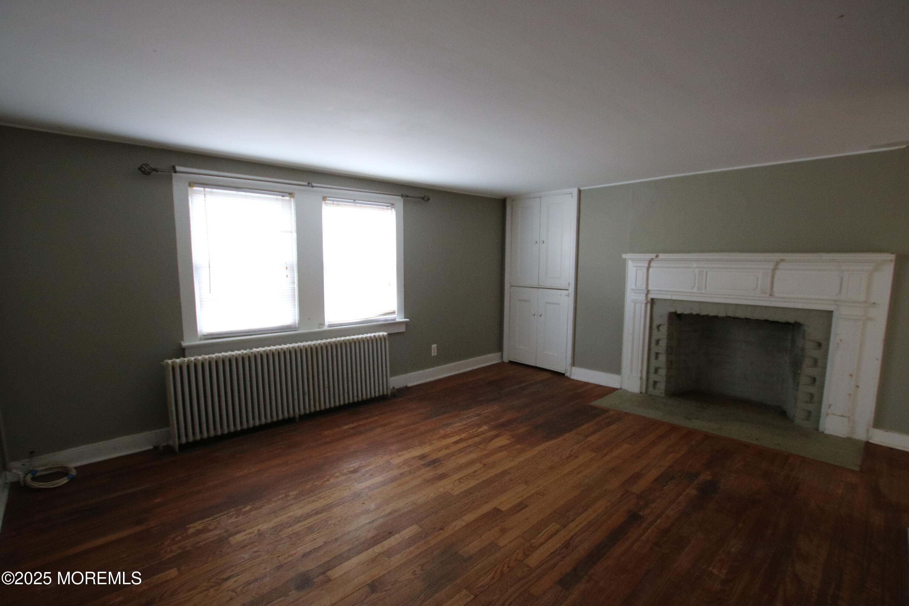 185 Monmouth Road West Long Branch, NJ 07764 - Photo 8 of 28 an empty room with wooden floor a fireplace and windows