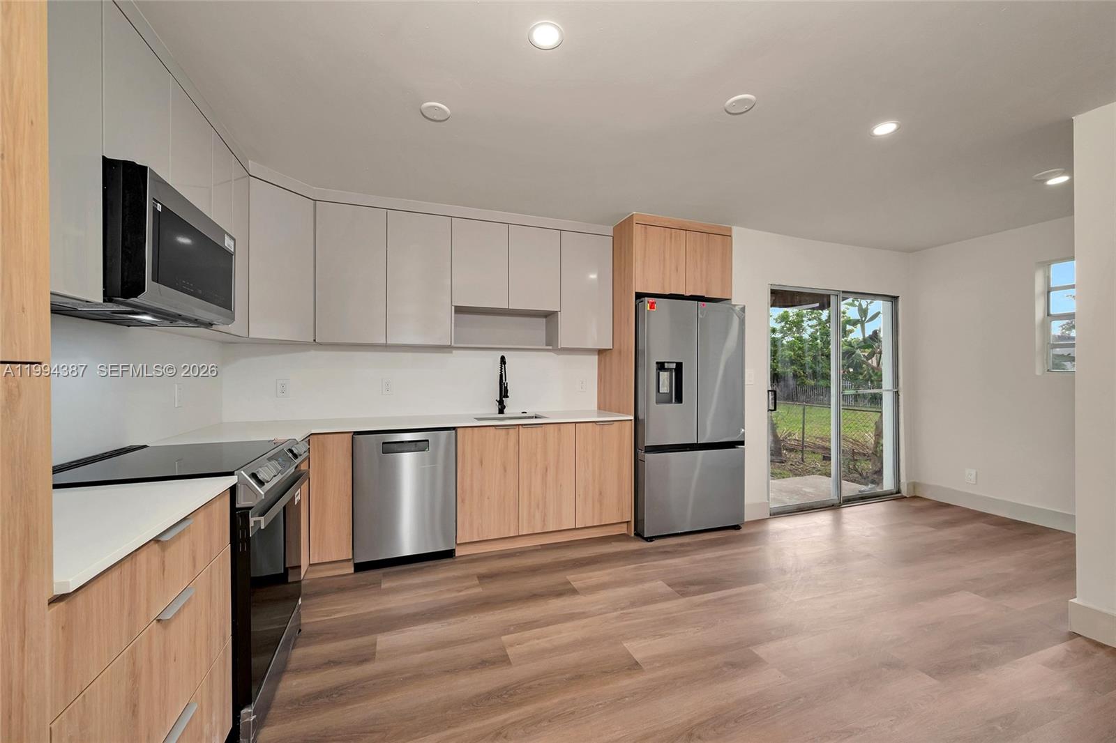 5632 Southwest 19th Street West Park, FL 33023 - Photo 8 of 43 a kitchen with a refrigerator a stove top oven a sink and dishwasher with wooden floor