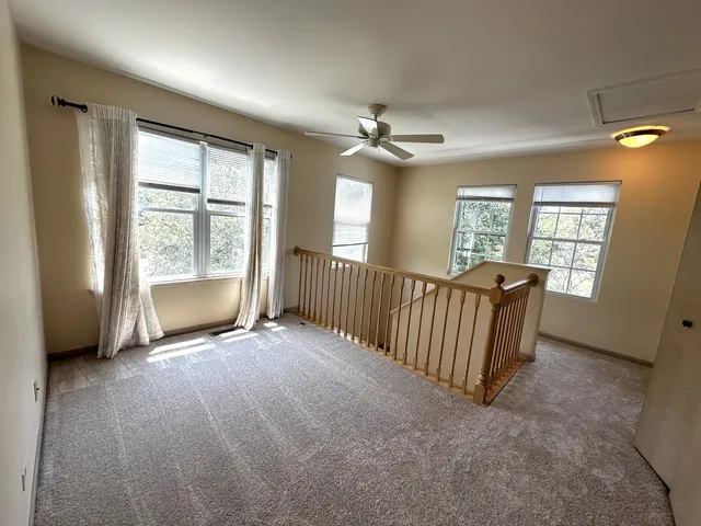 an empty room with windows and ceiling fan