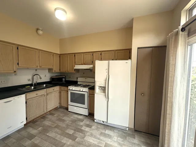 a kitchen with stainless steel appliances granite countertop a refrigerator a sink a stove and white cabinets with wooden floor