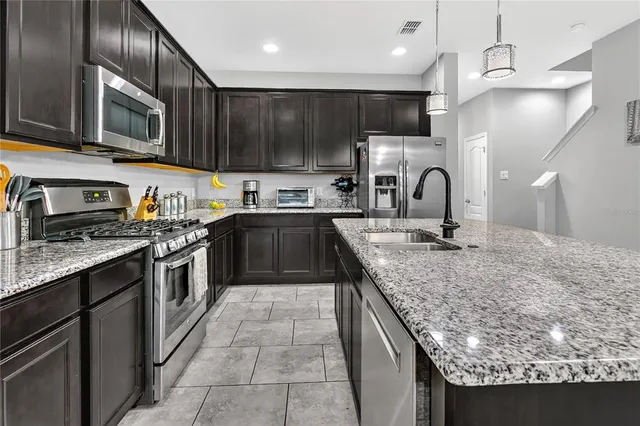a kitchen with stainless steel appliances granite countertop a sink a stove top oven a refrigerator and dishwasher