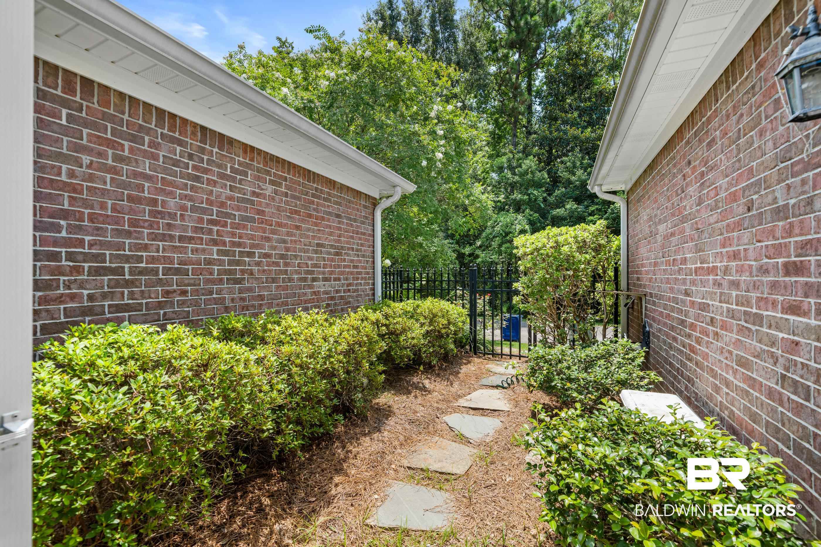 303 Savannah Circle Foley, AL 36535 - Photo 27 of 34 This exterior walkway features brick walls, a stone path, and manicured shrubbery