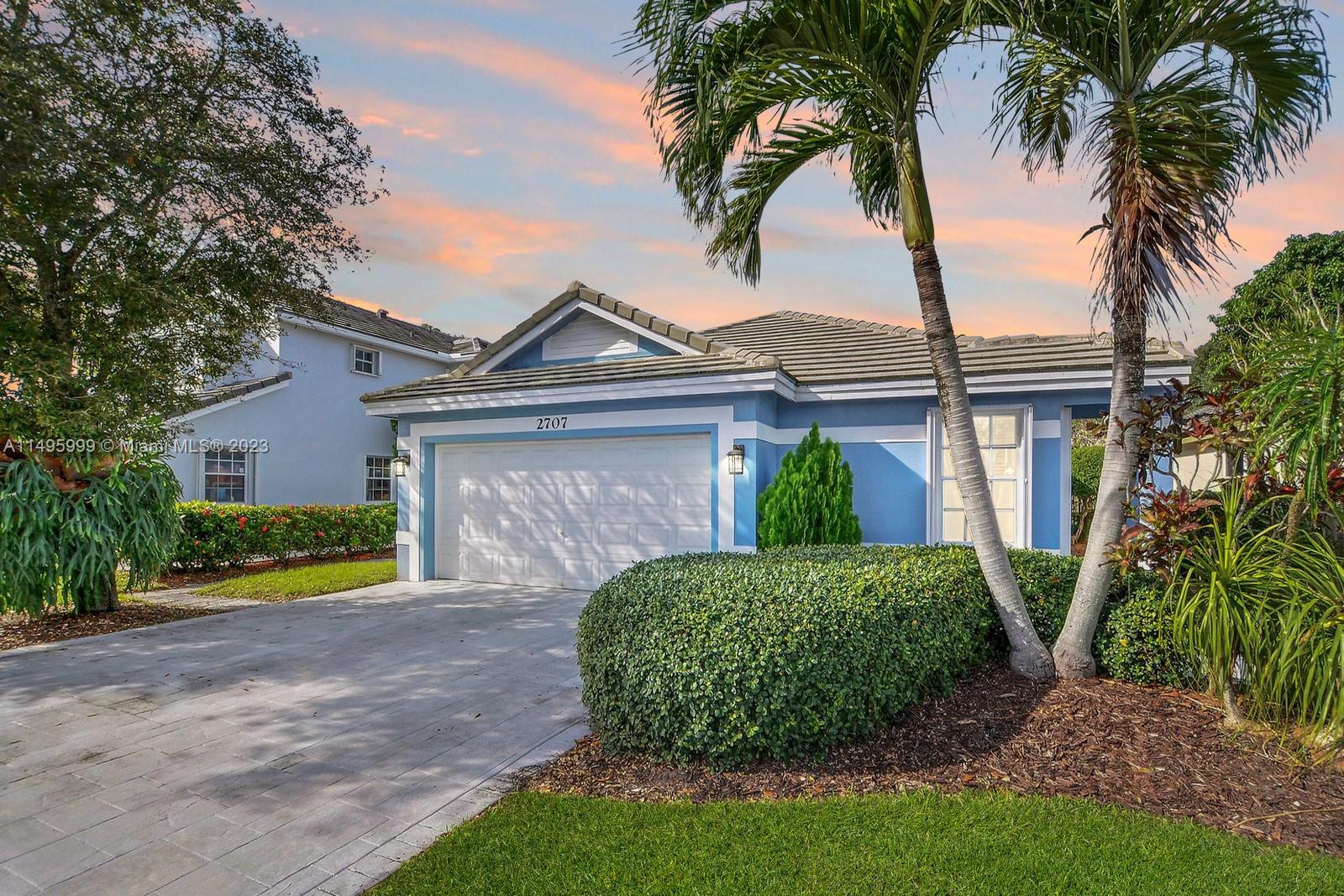a view of a house with a yard and palm trees