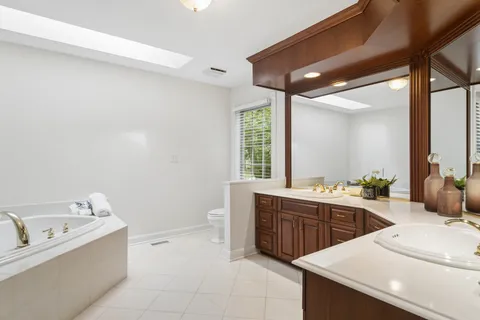 a large bathroom with a tub sink and mirror