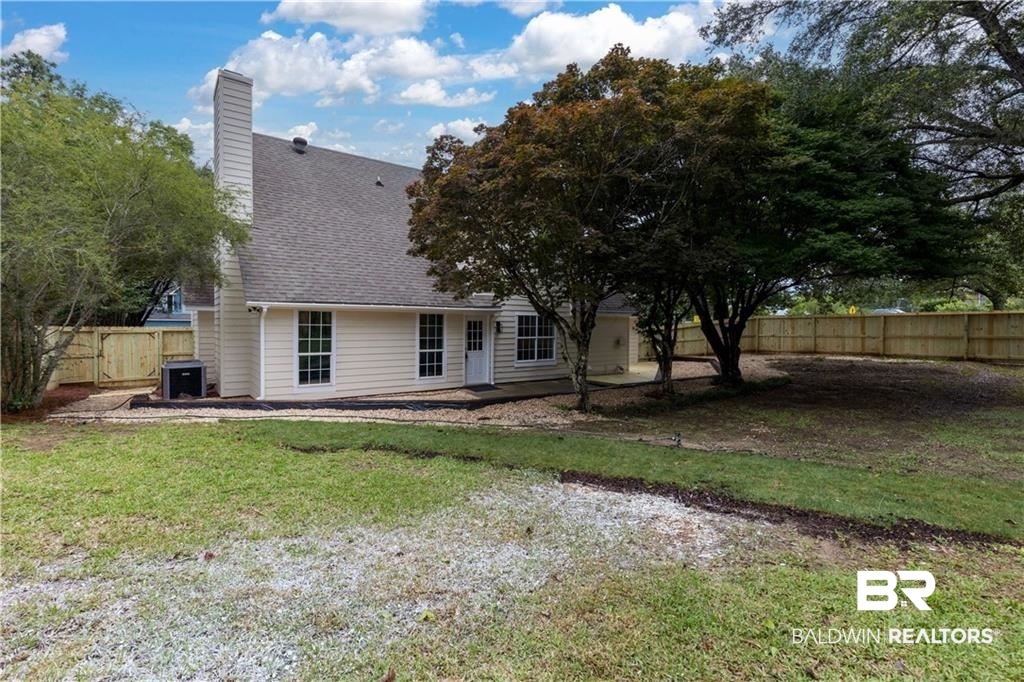 101 Lawson Road Daphne, AL 36526 - Photo 18 of 20 Expansive backyard featuring a new wood fence, mature trees, a concrete patio, and a light-colored siding exterior with white window frames