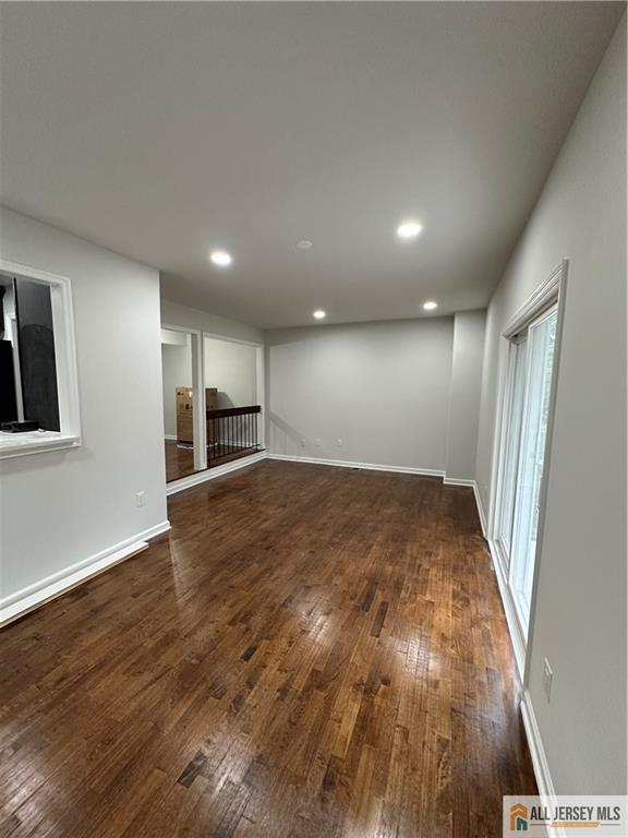 3303 Hana Road Edison, NJ 08817 - Photo 22 of 47 an empty room with wooden floor and a kitchen
