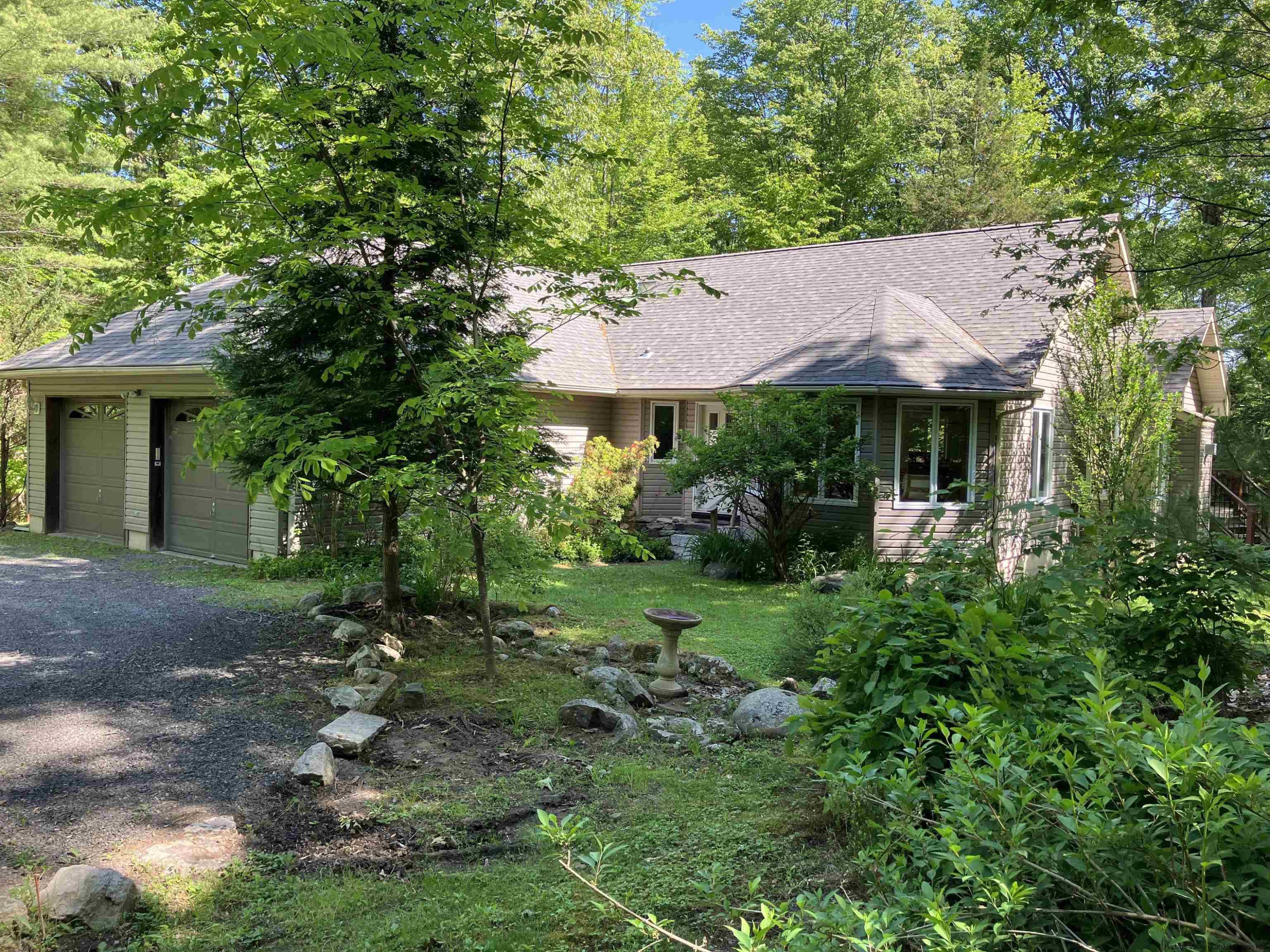 a backyard of a house with plants and large tree