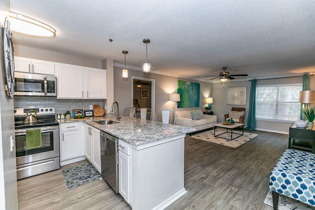 a kitchen with stainless steel appliances granite countertop a stove oven and a dining table with wooden floor