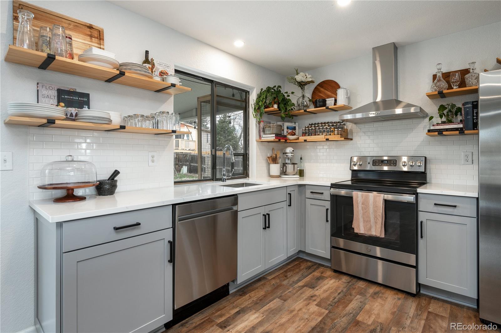 a kitchen with stainless steel appliances granite countertop a sink and wooden floors