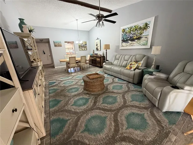a living room with furniture a flat screen tv and a ceiling fan