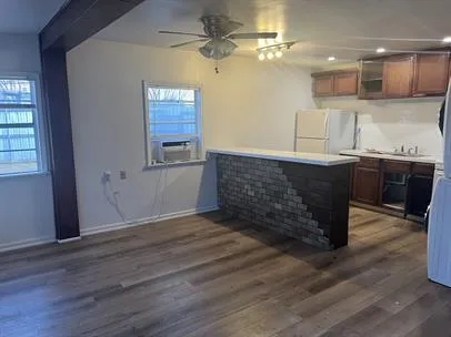 an empty room with wooden floor and kitchen view