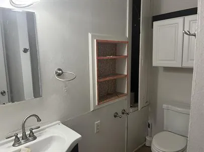 a bathroom with a granite countertop toilet and a sink