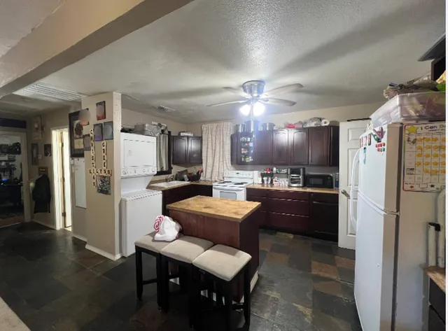 a large kitchen with a refrigerator a sink dishwasher a dining table and chairs with wooden floor