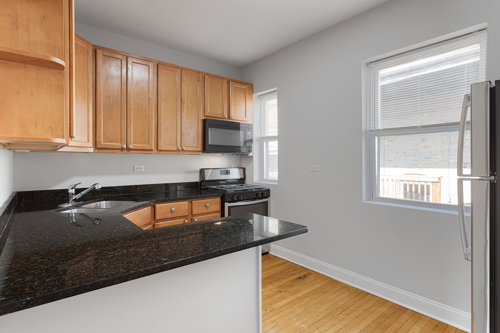 7328 North Damen Avenue, Unit 3 Chicago, IL 60645 - Photo 5 of 14 a kitchen with granite countertop a sink a stove and a microwave