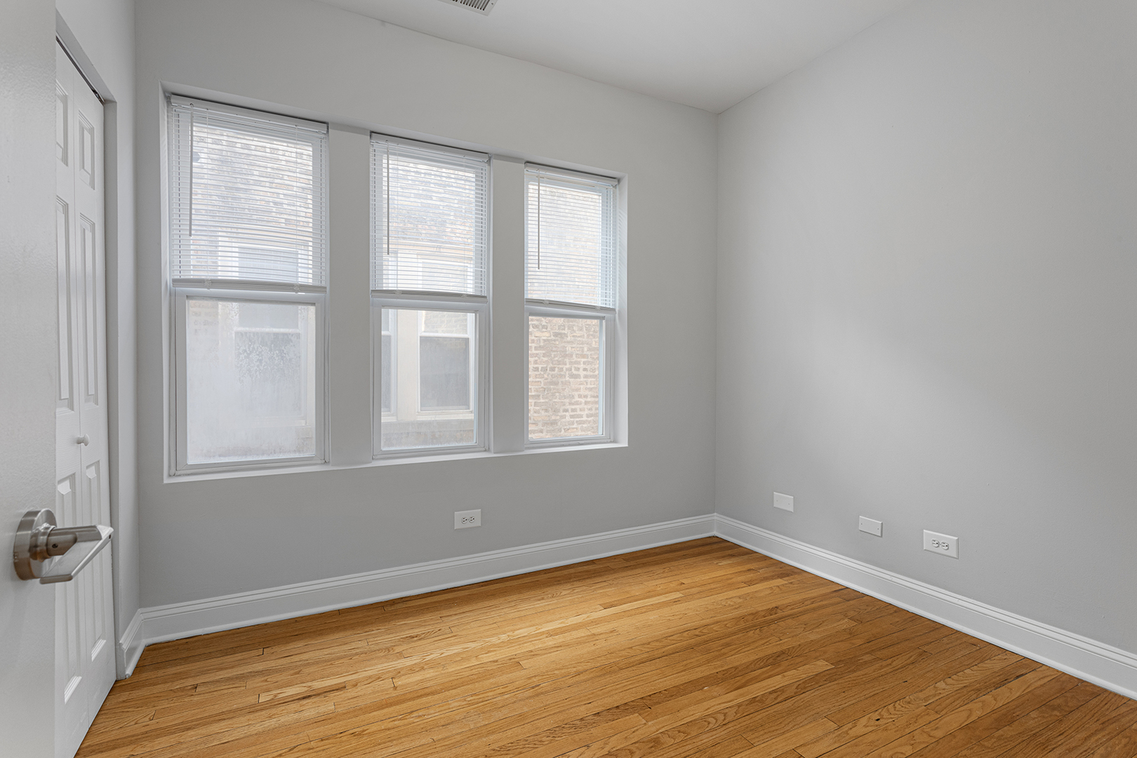 7328 North Damen Avenue, Unit 3 Chicago, IL 60645 - Photo 9 of 14 an empty room with wooden floor and windows