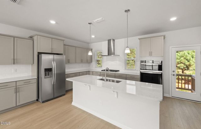 a kitchen with kitchen island a counter top space a sink stainless steel appliances and cabinets