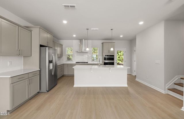 a large kitchen with stainless steel appliances kitchen island a large counter top and a stove top oven