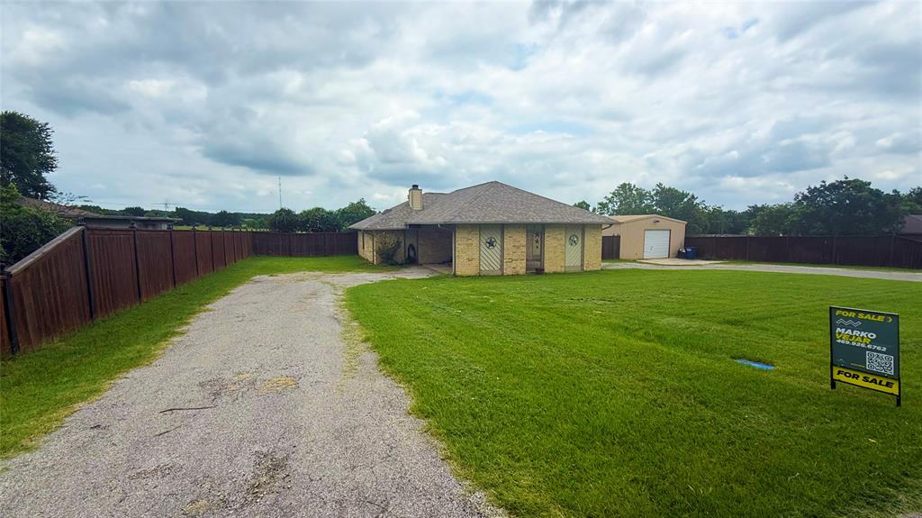 1356 Kerry Lane Azle, TX 76020 - Photo 2 of 27 Expansive property featuring a gravel driveway, a single-story residence with a light brick exterior, a detached garage, and a privacy fence enclosing the perimeter