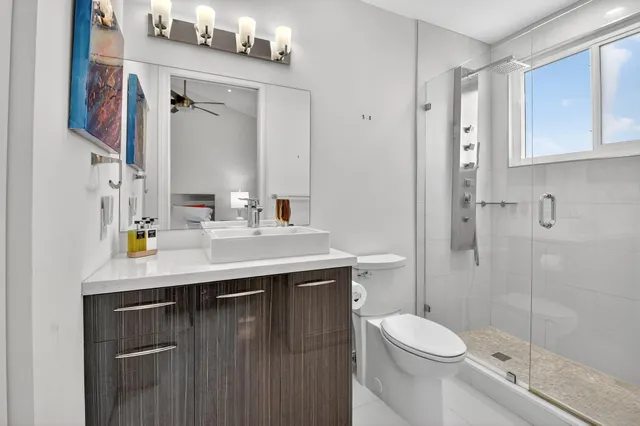 a bathroom with a double vanity sink toilet mirror and shower