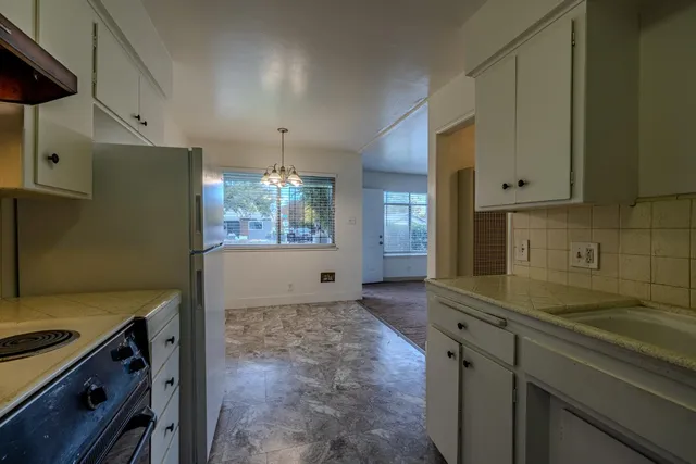 a kitchen with granite countertop a sink stove and cabinets