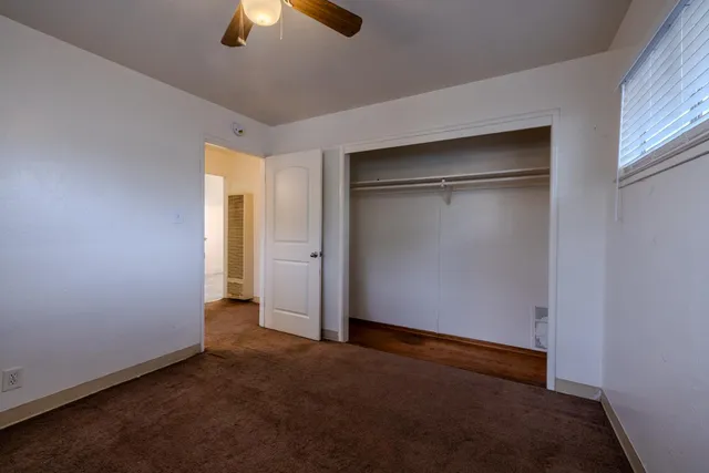 an empty room with closet and a chandelier fan