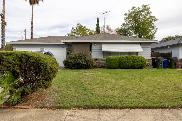 a front view of a house with a yard and potted plants