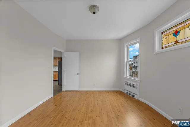 a view of an empty room with a window and wooden floor