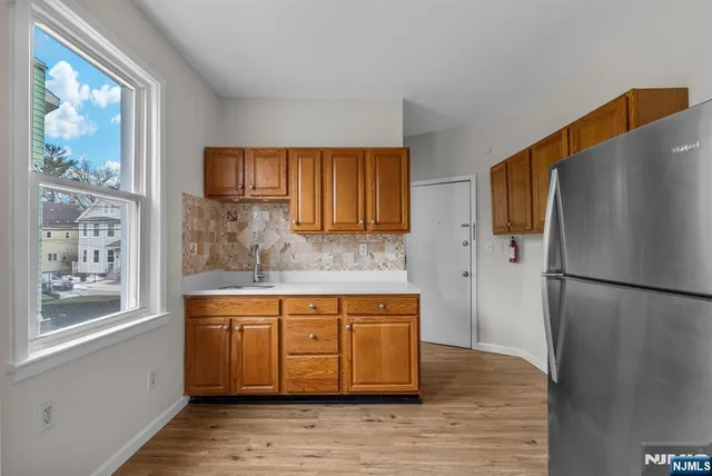 a kitchen with stainless steel appliances granite countertop a refrigerator a sink and a stove with wooden floors