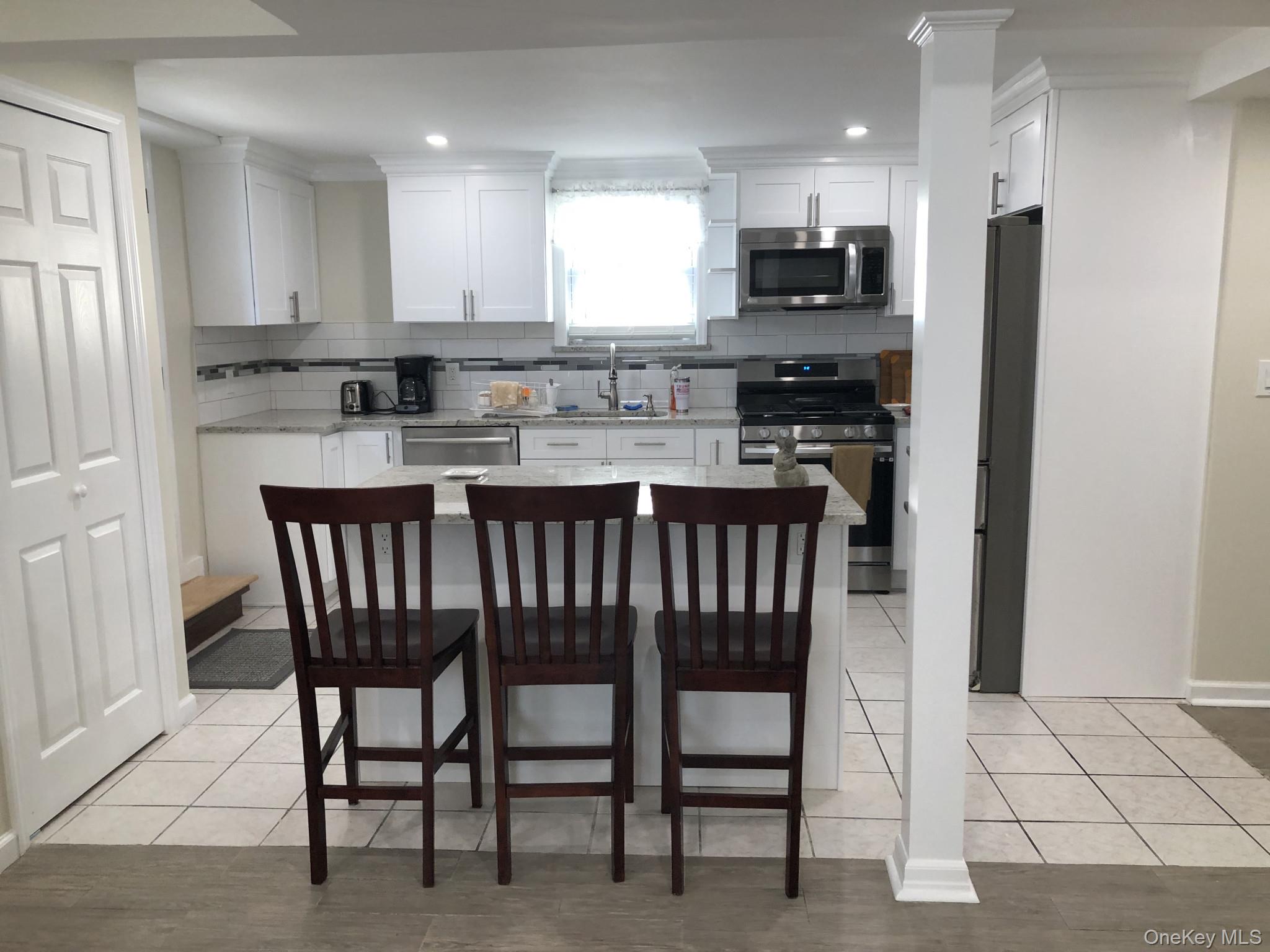 321 West Walnut Street, Unit 2 Long Beach, NY 11561 - Photo 3 of 13 a kitchen with stainless steel appliances granite countertop a stove a refrigerator a sink a dining table and chairs