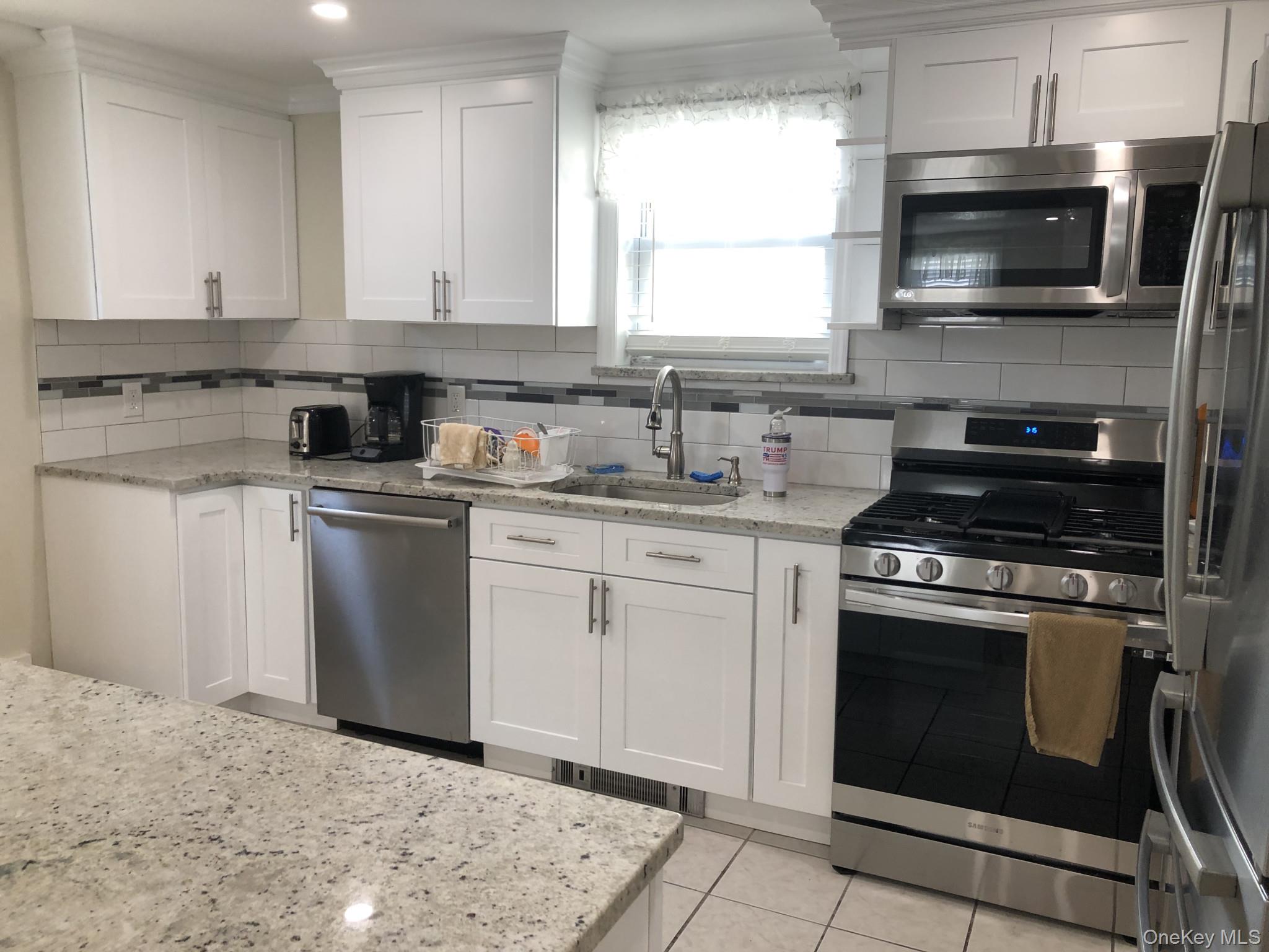 321 West Walnut Street, Unit 2 Long Beach, NY 11561 - Photo 5 of 13 a kitchen with stainless steel appliances granite countertop a stove sink microwave and cabinets