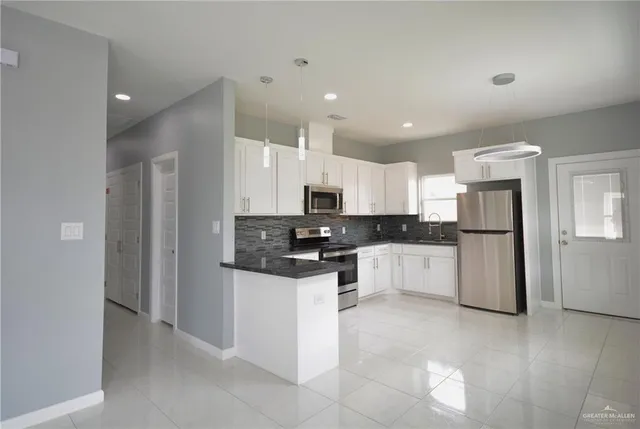 a kitchen with white cabinets and stainless steel appliances