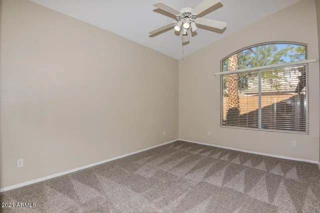 an empty room with chandelier fan and windows