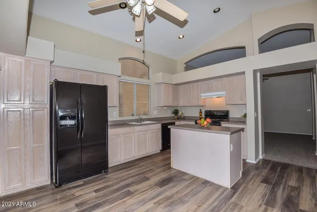 a kitchen with stainless steel appliances a refrigerator a sink dishwasher a stove and white cabinets with wooden floor