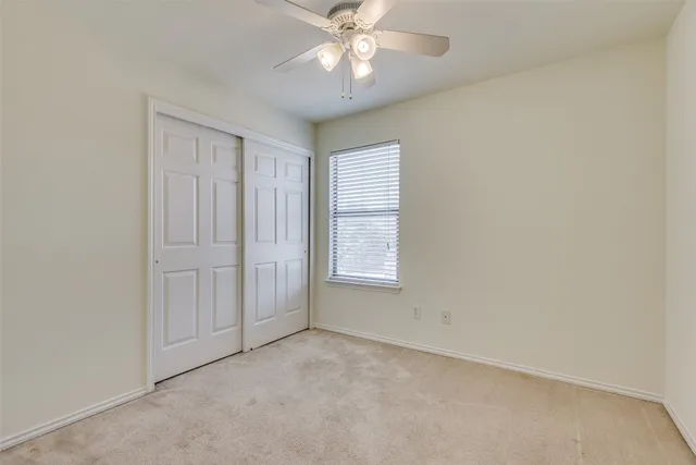 an empty room with chandelier fan and windows