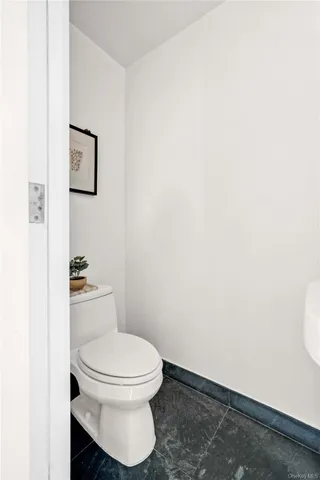 a white toilet sitting next to a white wall