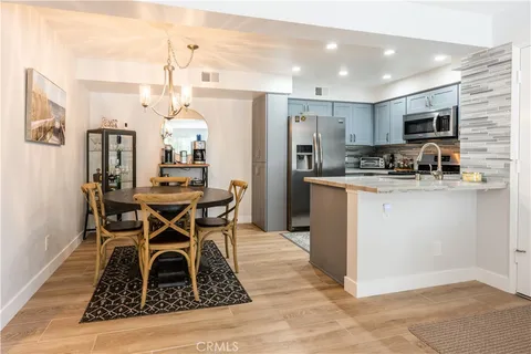 a kitchen with stainless steel appliances kitchen island granite countertop a sink a stove a refrigerator cabinets and chairs