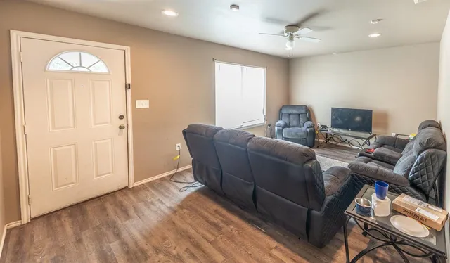 a living room with furniture a ceiling fan and a wooden floor