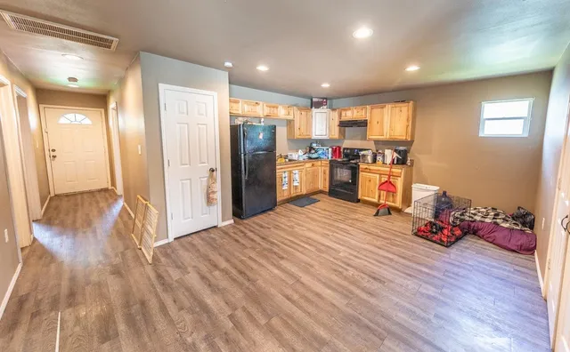 a view of a kitchen with refrigerator and wooden floor
