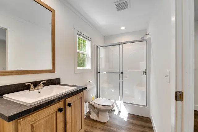 a bathroom with a granite countertop sink toilet a mirror and shower