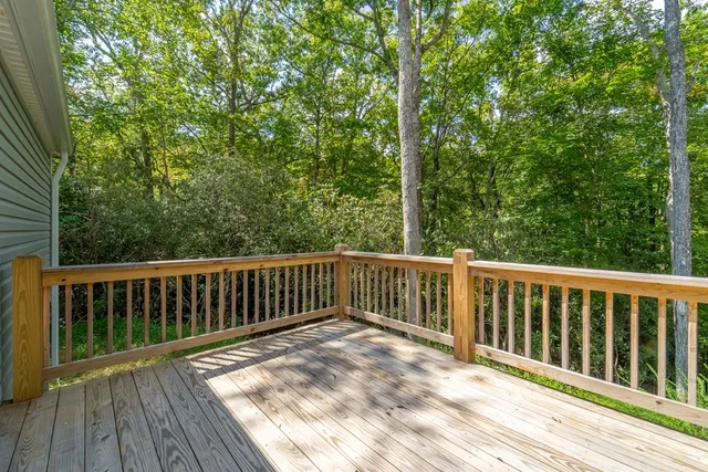 a balcony with wooden floor and trees in the back