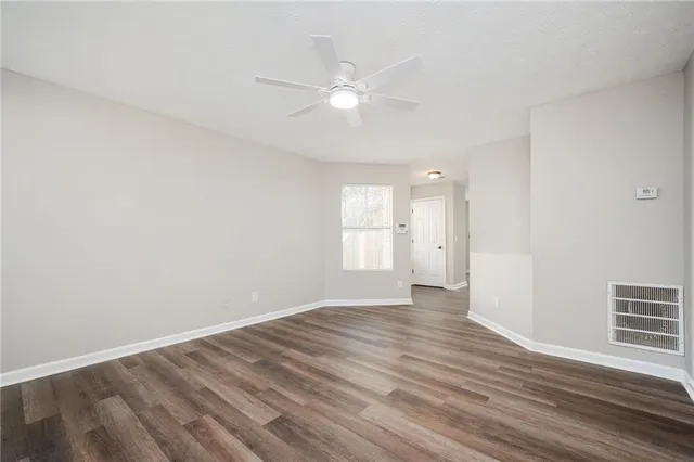 a view of an empty room with wooden floor and a window