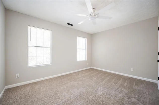 an empty room with windows and fan