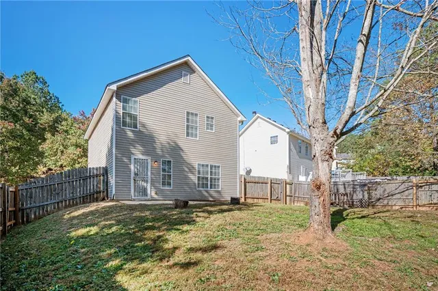 a view of a house with backyard and trees